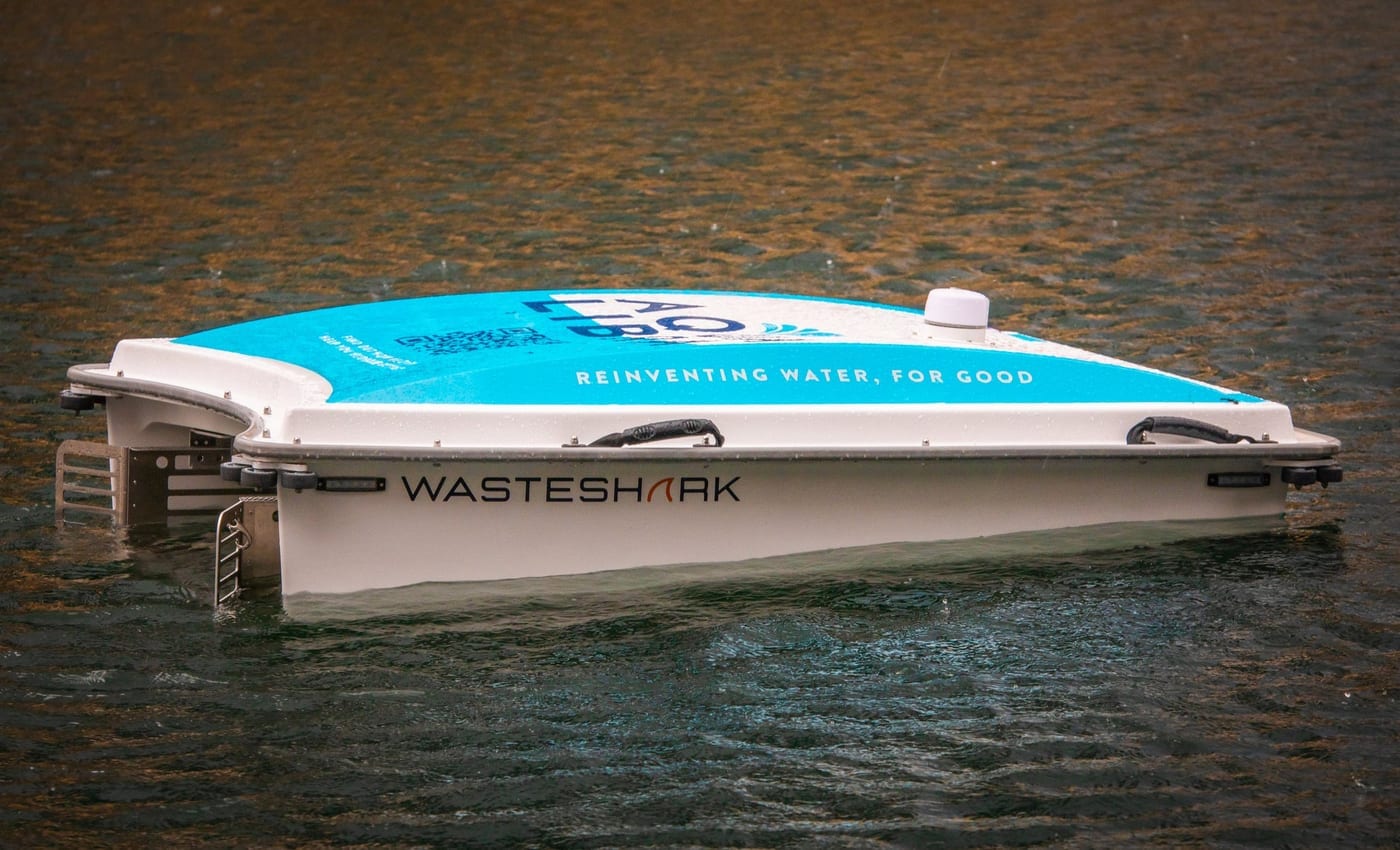 An Aqualibra branded WasteShark drone on dark water, its teal livery reading Reinventing Water, For Good.