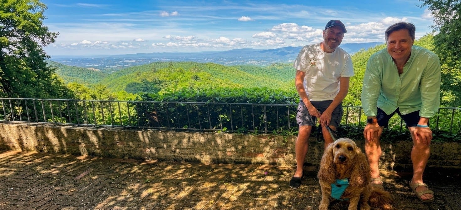 Andrew Douglas and Patrick Day crouched with their dog on a terrace above a Tuscan valley