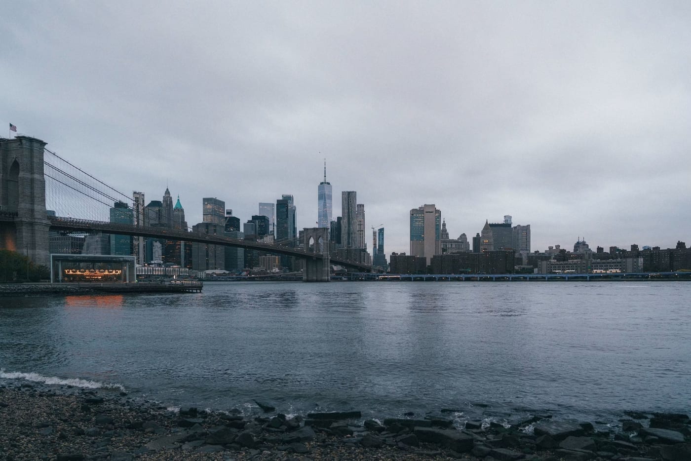 The Manhattan skyline and Brooklyn Bridge seen across the East River on an overcast morning.